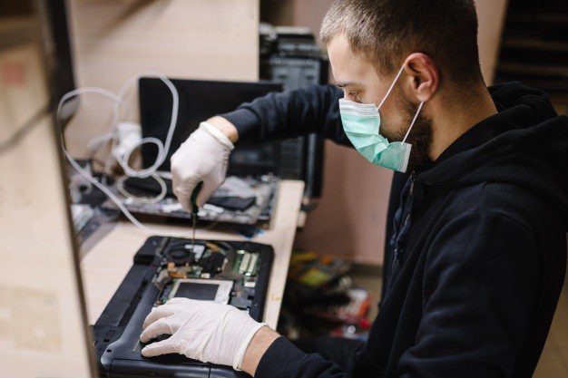 tecnico reparando computadora portatil laboratorio hombre trabajando mascara protectora taller 180731 201