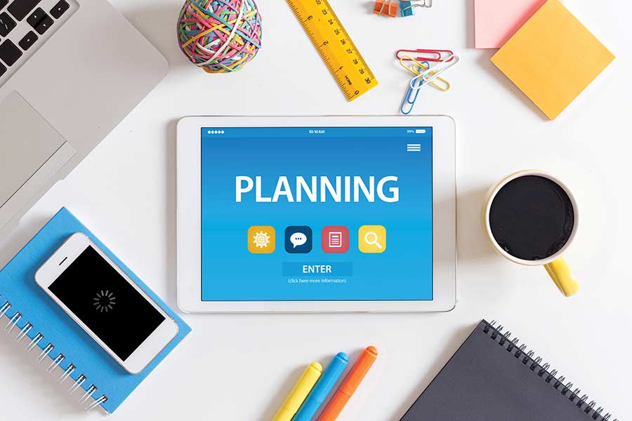 Tablet con la palabra "planning" y objetos escolares alrededor